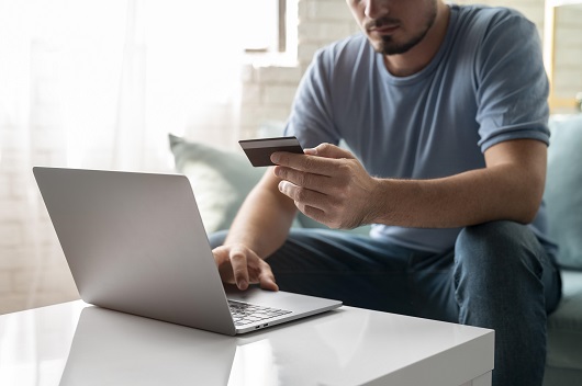 hombre usando su tarjeta de credito para jugar en linea para un pedido