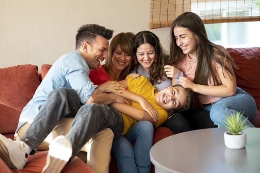 familia con padres e hijos divirtiendose juntos en el sofa1