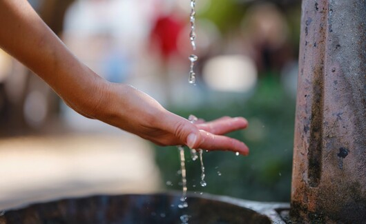 Tercer bono azul de COFIDE capta S/ 120 millones 1 Mano recibiendo agua en un grifo